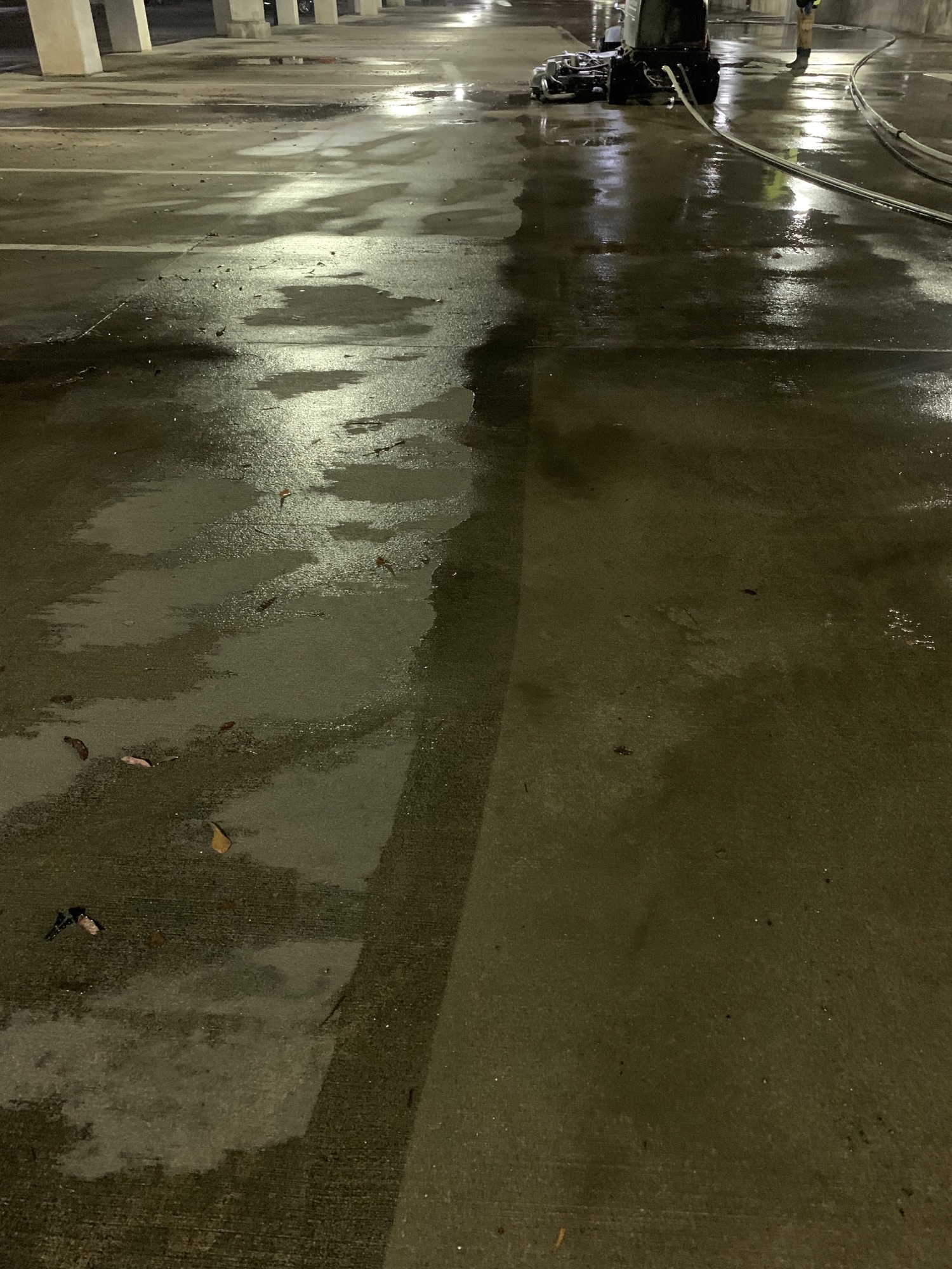 Partially wet parking garage floor with a cleaning machine.