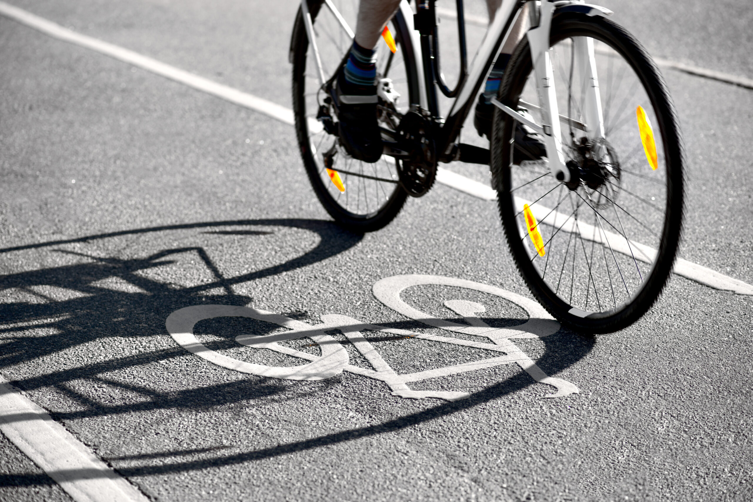 Bicycle riding over a painted bike symbol on asphalt.